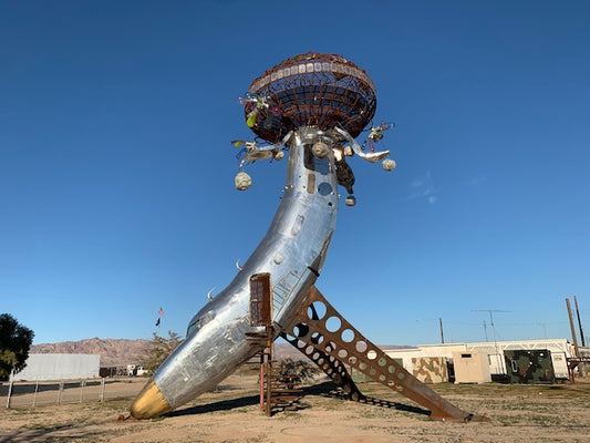 a strange, metallic, art installation that may have been part of a plane before it was converted to something that looks like a mirrored disco ball agains the blue sky in the middle of the desert.