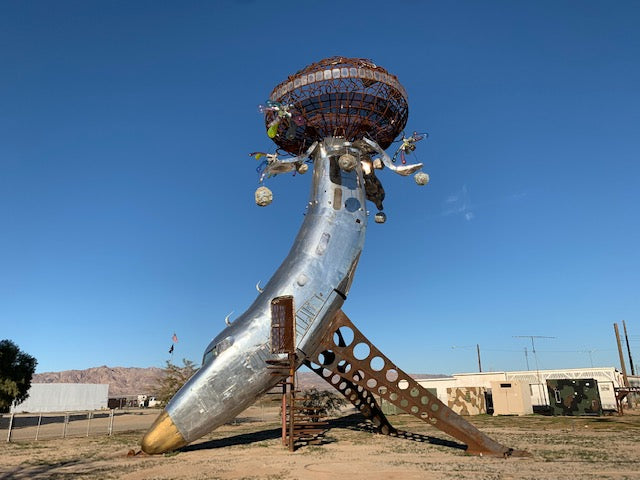 a strange, metallic, art installation that may have been part of a plane before it was converted to something that looks like a mirrored disco ball agains the blue sky in the middle of the desert. 
